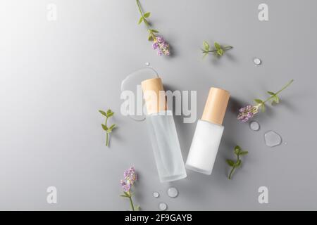 Eine Draufsicht auf Hautpflegeflaschen auf einer Oberfläche mit Lavendelblüte Stockfoto