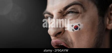 Ein schreiender Mann mit dem Bild des Südkoreaners Nationalflagge auf seinem Gesicht Stockfoto