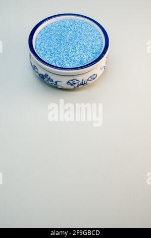 Eine vertikale Aufnahme von blauem Sand in einer porzellanschale Auf einer weißen Oberfläche Stockfoto