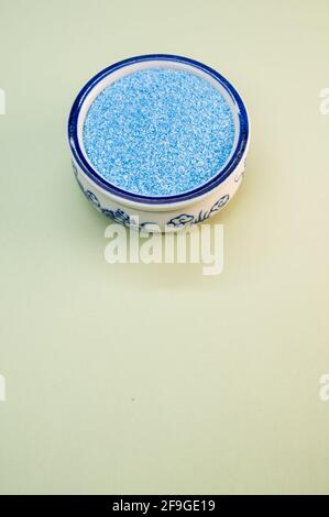 Eine vertikale Aufnahme von blauem Sand in einer porzellanschale Auf einer weißen Oberfläche Stockfoto