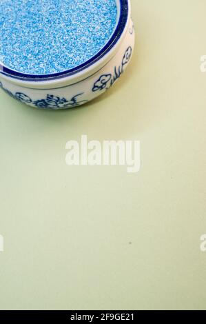 Eine vertikale Aufnahme von blauem Sand in einer porzellanschale Auf einer weißen Oberfläche Stockfoto