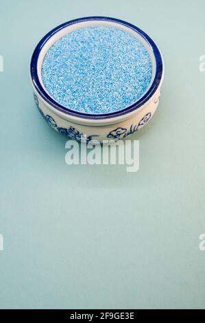 Eine vertikale Aufnahme von blauem Sand in einer porzellanschale Auf einer weißen Oberfläche Stockfoto