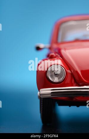 Nahaufnahme eines roten Spielzeugmodellautos mit halber Vorderansicht auf blauem Hintergrund. Stockfoto