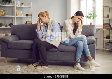 Die tausendjährige Tochter und die ältere Mutter sitzen Seite an Seite und vermeiden Gespräche nach einem Streit. Stockfoto