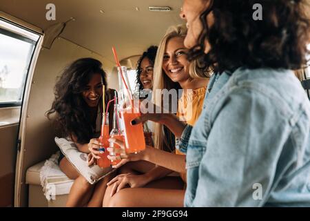 Vier Frauen trinken Cocktails im Wohnmobil und genießen den Sommer Stockfoto