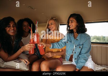 Eine Gruppe von verschiedenen Freundinnen, die ihren Urlaub feiern. Vier Frauen sitzen bei Cocktails Stockfoto