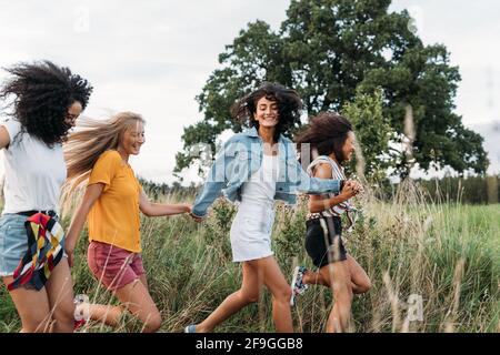 Gruppe einer glücklichen Frau, die im Freien läuft und springt. Weibliche Freunde, die Spaß haben Stockfoto