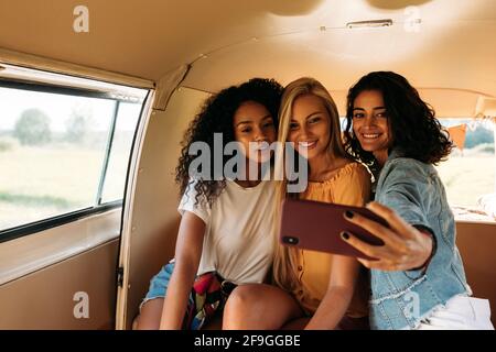 Eine Gruppe weiblicher Freunde auf einem Autoreise, die Selfie machen Stockfoto