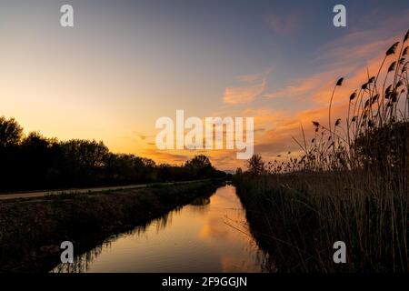 Fluss, der rote Wolken während des Sonnenuntergangs reflektiert. Stockfoto