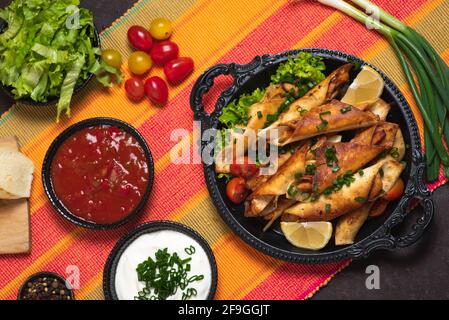 Hausgemachte kleine Tacos mit Huhn, Dip-Saucen und Lebensmittelzutaten genannt Taquitos Stockfoto