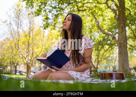 Schöne Latina Teen Songwriter im Park im leichten Frühling Kleid Stockfoto