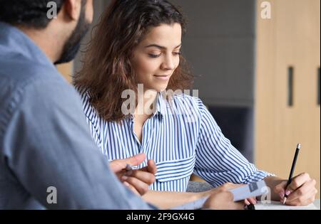 Zwei Vertriebsmitarbeiter arbeiten im Büro mit einem Laptop zusammen. Stockfoto