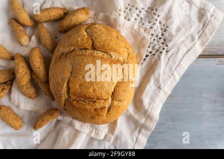 Ein Schuss von einem hausgemachten traditionellen runden Brot und Brotstangen auf einem rustikalen Holztisch Stockfoto