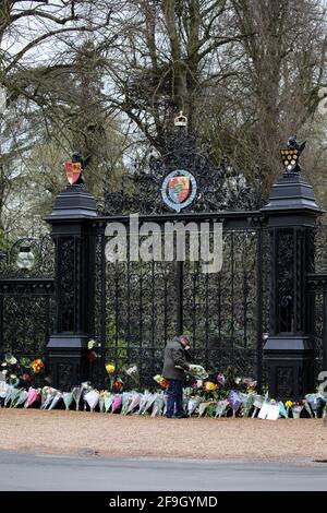 Sandringham, Großbritannien. April 2021. Ein Mann stellt Blumen vor die Norwich Gates, da Sandringham am Tag nach dem Vergehen von Prinz Philip, Herzog von Edinburgh, sehr düster ist. Vor den Toren Norwich, im Sandringham House, Norfolk, haben Menschen Blumen gezollt, was der Winterrückzug von Königin Elizabeth II. Ist Prinz Philip hat seit seiner Pensionierung im Jahr 2017 einen Großteil seiner Zeit in der Gegend von Sandringham verbracht. Kredit: Paul Marriott/Alamy Live Nachrichten Stockfoto