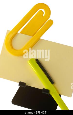 Office Memo ist bereit, auf gelbem Papier mit Stift und Büroklammer fertig zu schreiben. Die Büroklammer ist gigantischer Größe, so dass Sie sie nicht vergessen werden. Stockfoto