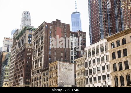 Gesichter der eklektischen Mischung aus älteren und neueren Gebäuden in Downtown Manhattan, einschließlich des Freedom Tower, der sich im Hintergrund abzeichnet. Stockfoto