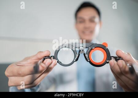 Ein männlicher Arzt hält einen Augentest Messhilfe in Eine Augenklinik Stockfoto