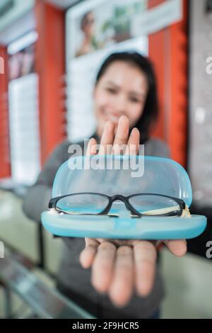 Selektiver Fokus der Brille in der Brillenbox mit Der Hintergrund einer schönen lächelnden Frau Stockfoto