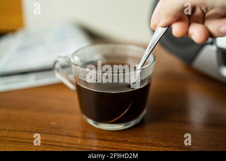 Rühren Sie den Kaffee in einer Tasse mit Teelöffel Stockfoto