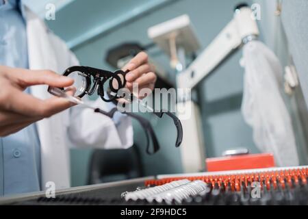 Die Hand eines Augenarztes nimmt eine Testbrille auf Messgerät in einer Box mit einem Satz Linsen Stockfoto