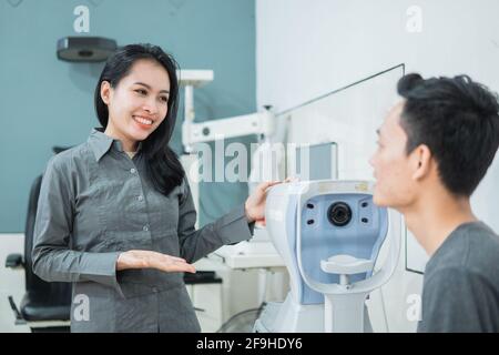 Eine Ärztin, die ein Gerät zusammen mit einem männlichen Patienten verwendet Im Untersuchungsraum Stockfoto