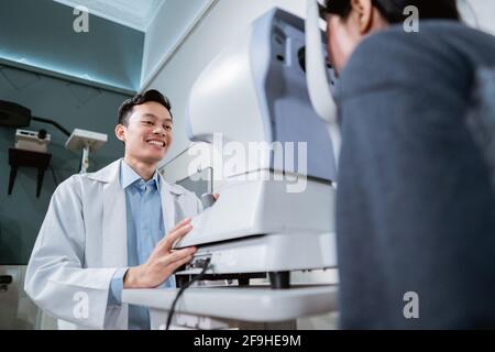 Ein Arzt und eine Patientin, die ein Auge tut Überprüfen Sie mit einem Gerät Stockfoto