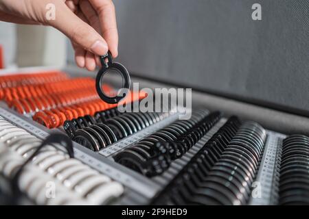 Die Hand eines Augenarztes nimmt eine Testbrille auf Messgerät in einer Box mit einem Satz Linsen Stockfoto