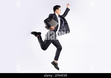Junger asiatischer Geschäftsmann springt auf weißem Hintergrund Stockfoto
