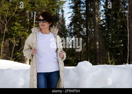 Weißes Fleece-Sweatshirt mit Rundhalsausschnitt, Mockup mit einer Frau mit asymmetrischer Frisur im Winterholz. Vorlage für schweres Sweatshirt Stockfoto