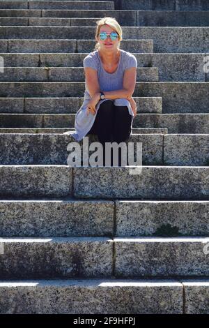 Frau Tourist auf Treppen von Rhodos Memorial mit Reflexion von Löwen in Sonnenbrillen Stockfoto