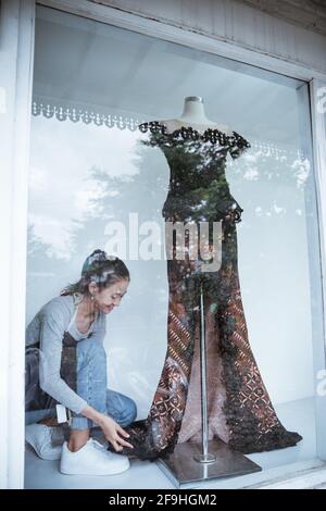 Porträts von jungen Frauen in Glasfenstern Reinigung und Verkauf Traditionelle Batik-Kleidung Stockfoto