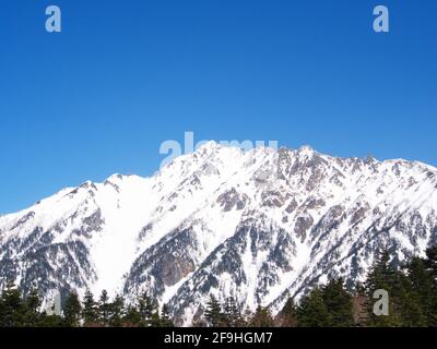 Ein Blick auf den Schneeberg von der Shinhotaka-Seilbahn im Bergpark der Gifu-Präfektur am Frühlingstag mit grünen Kiefernwäldern. In der Nähe von Takayama City, Japan in Stockfoto
