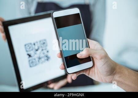 Nahaufnahme Ladenbesitzer dienen Kunden qris Barcode Stockfoto