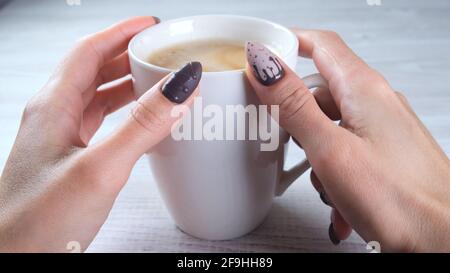 Schöne gepflegte Nägel in Form von Schokolade Bonbons auf weibliche Hände close-up und eine Tasse Kaffee. Stockfoto