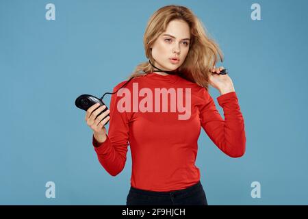Hübsche Frau in rot Pullover Joystick Controller Set-Top-Box blau Hintergrund Stockfoto