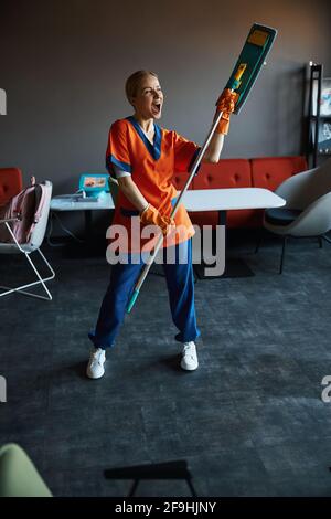 Hochmütig arbeitende Arbeitnehmerin, die sich während der Säuberung amüsieren kann Stockfoto