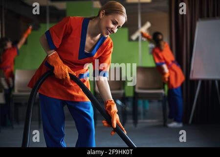 Gruppe von Hausmeisterinnen mit Gummihandschuhen, die das Büro reinigen Stockfoto