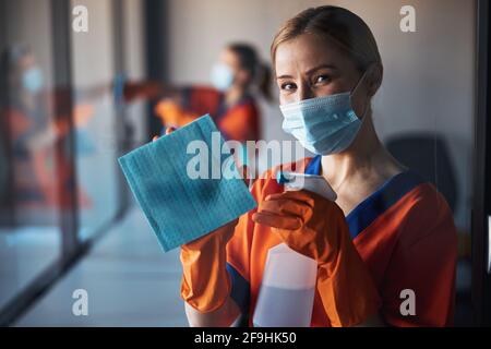 Reiniger, der die Glaswand mit einem feuchten saugfähigen Tuch abwischt Stockfoto