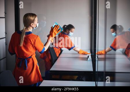 Zwei Putzfrauen in Gesichtsmasken desinfizieren Büroflächen Stockfoto