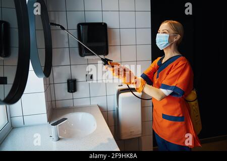 Putzfrau in der Uniform, die das Bad desinfiziert Stockfoto