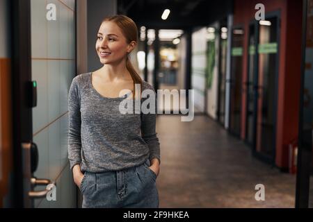 Glückliche weibliche Büroangestellte, die im Korridor träumte Stockfoto