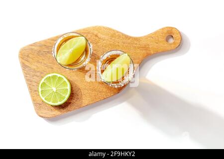 Tequila-Schüsse wurden auf einem Holzbrett mit Limettenscheiben serviert Stockfoto