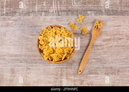 Farfalle Pasta in Holzschüssel mit Gabel. Ungekochte getrocknete Hartweizengrieß-Nudeln. Italienische Nudeln. Stockfoto