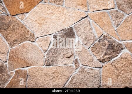 Wandstruktur aus braunem Stein, grunge Hintergrund, abstraktes Mosaikmuster, Felsoberfläche, schmutziger, rauer Granit. Verwitterte Gebäudefassade. Natürliche Textur Stockfoto