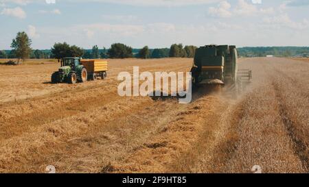 Warschau, Polen 10.08.2020 - ein landwirtschaftliches Feld mit zwei großen Traktoren während des Tages. Ernte und Kultivierung des Feldes. Bäume mit wolkenblauem Himmel im Hintergrund. Stockfoto