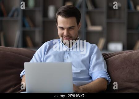 Glücklicher kaukasischer Mann arbeitet zu Hause am Laptop Stockfoto