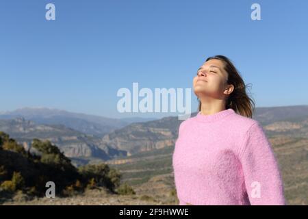 Entspannte Frau in Rosa, die frische Luft im Berg atmet Stockfoto