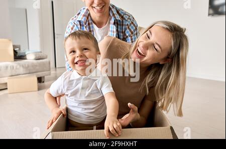 Nette aufgeregt Kind Sohn Reiten in Box am bewegenden Tag mit den Eltern in neuem Zuhause. Stockfoto