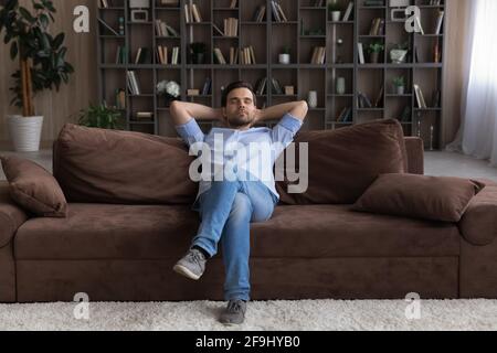 Ruhiger junger Mann, der sich auf dem Sofa entspannt und ein Nickerchen macht Stockfoto