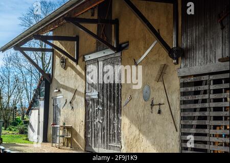 Alte abgenutzte Tür zur ländlichen Scheune und Werkzeuge, die an der Wand hängen Stockfoto